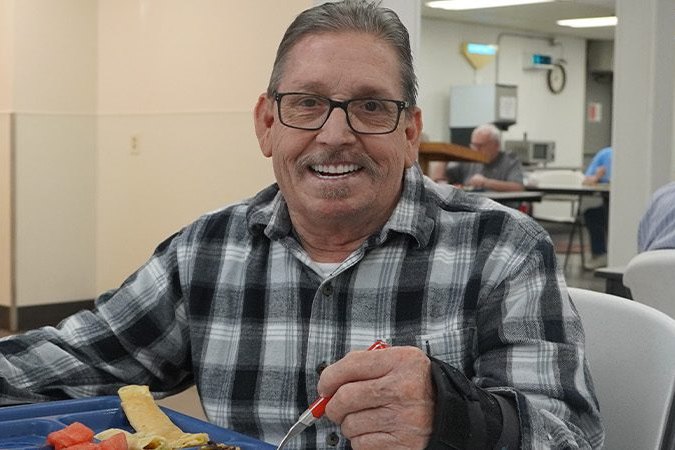 A man smiling over a hot meal in the dining room at the Boise Rescue Mission