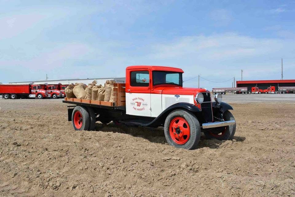 A restored 1930s Ford farm truck loaded with burlap potato sacks, lettered Wada Farms Fine Produce Since 1943